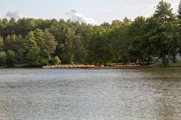 Beautiful summer landscape of blue sky in the clouds and a picturesque lake, surrounded by coniferous and deciduous forest.