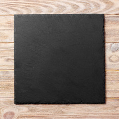 Fototapeta premium square plate on table. black dish on wooden background. copy space