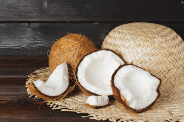 Cracked coconut pieces on dark wooden background
