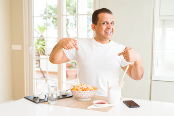 Middle age man eating asian food with chopsticks at home looking confident with smile on face, pointing oneself with fingers proud and happy.