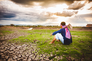 Fototapeta premium Hopeless Farmer sitting on dry ground with hoe beside him. Global warming crisis, Economic crisis concept