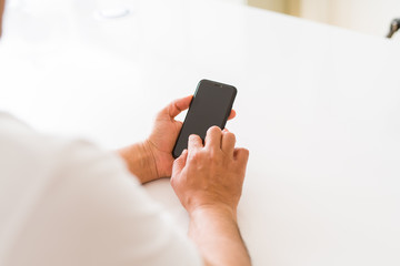 Close up of middle age man hands using smartphone at home