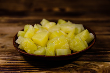 Ceramic plate with chopped canned pineapple on wooden table