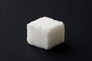 Single cube of sugar on black background