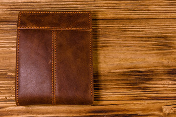 Closed brown leather wallet on wooden table. Top view