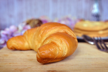 Delicious looking traditional French croissant on wooden plate