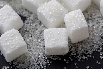 Closeup of granulated and sugar cube on black background