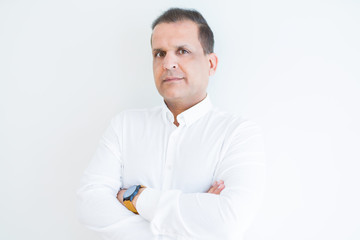 Middle age business man looking natural and relaxed with crossed arms over white wall background