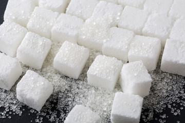 Closeup of granulated and sugar cube on black background