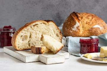 Toasted white artisan bread with butter and jam on light grey stone table. Simple breakfast.