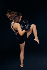 Athletic woman in boxing gloves is practicing karate in studio.
