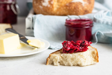 Toasted white artisan bread with butter and jam on light grey stone table. Simple breakfast.