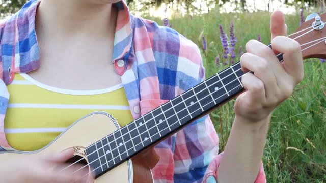 girl playing on ukulele in evening meadow