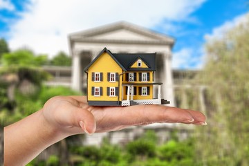 Building, mortgage, real estate and property concept - close up of hands holding house model