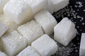 Closeup of granulated and sugar cube on black background