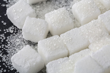 Closeup of granulated and sugar cube on black background