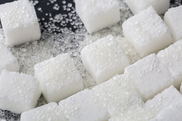 Closeup of granulated and sugar cube on black background