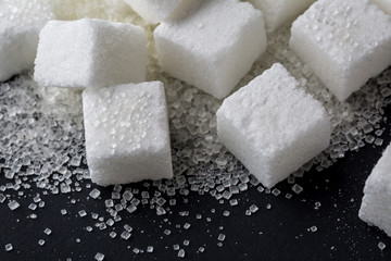 Closeup of granulated and sugar cube on black background