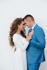 Cute couple embracing looking one to another on dating. A love story. Romantic moment. Happy girl in white dress and guy posing in blue suit and tie.