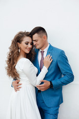 Cute couple embracing looking one to another on dating. A love story. Romantic moment. Happy girl in white dress and guy posing in blue suit and tie.
