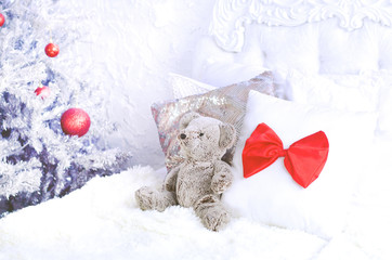 Teddy bear in bed near the Christmas tree.