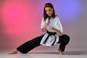Athletic woman in traditional kimono is practicing karate in studio. © nazarovsergey