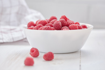 Common raspberries. Ripe red fruits in white bowl.