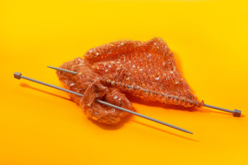 Tangle and knitting needles on yellow paper.