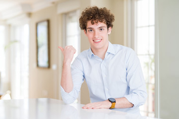 Fototapeta na wymiar Young business man with curly read head smiling with happy face looking and pointing to the side with thumb up.