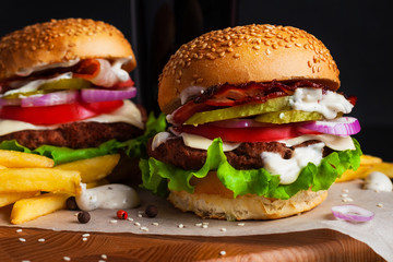 Beef burgers on a board with fries on a black background