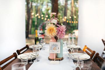 Elegant wedding table arrangement, floral decoration with peony, restaurant. Wedding table setup. Wedding in the forest. Seat numbers. - 282847575