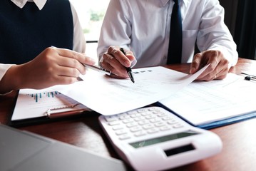 Businessman analyzing investment charts and pressing calculator buttons over documents. Accounting Concept.