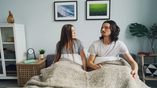 Husband And Wife Are Waking Up Together Sitting Up Then Going To Sleep Again In Bed At Home. Relaxation, Modern Lifestyle And Happy Married Couple Concept.