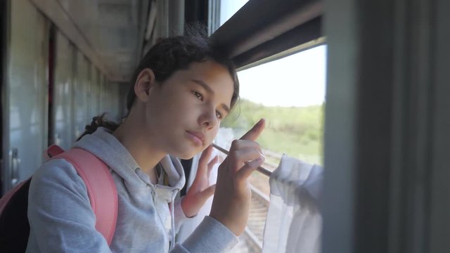sad girl looks out the train window. travel transportation railroad concept. teen girl misses traveling in a train compartment looking out the window lifestyle . long train journey by rail
