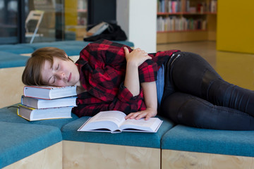 Tired student sleeping on books in the library