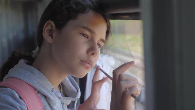 sad girl looks out the train window. travel transportation railroad concept. teen lifestyle girl misses traveling in a train compartment looking out the window. long train journey by rail