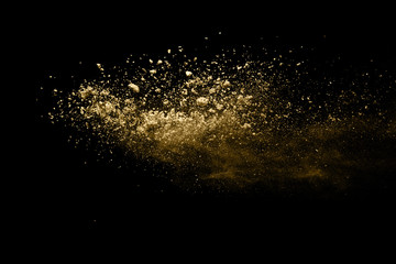 Golden powder explosion on black background. Freeze motion.