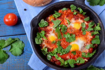 Shakshuka with tomato sauce and quail eggs topped with cilantro in a cast iron pan