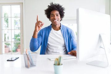 African American man working using computer surprised with an idea or question pointing finger with happy face, number one