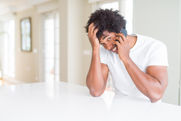 African American business man talking on the phone stressed with hand on head, shocked with shame and surprise face, angry and frustrated. Fear and upset for mistake.