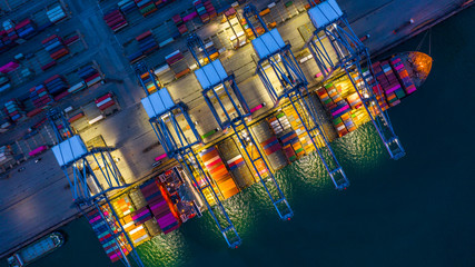 Container ship working at night, Business import export logistic and transportation of International by container ship in the open sea, Aerial view container ship loading and unloading at night.