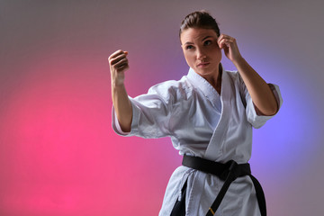 Athletic woman in traditional kimono is practicing karate in studio. © nazarovsergey