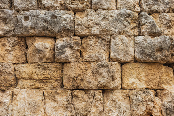 Closeup view of textured weathered ancient stone wall. Historical remains of times of Roman empire. Horizontal color photography.