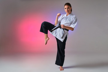 Athletic woman in traditional kimono is practicing karate in studio. © nazarovsergey