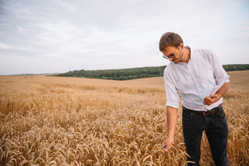 Naklejka na ściany i meble young farmer engineer standing on wheat field