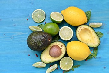 Top dish with raw food. Avocado, limes, lemons and mint on blue background. Copy space text.
