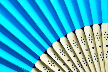 Detail of open blue folding hand fan. A fan provides cooling air during summer.