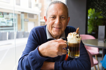 Handsome middle age senior man drinking coffee at restaurante, smiling happy enjoying and relaxing retirement