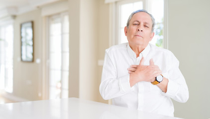 Obraz premium Handsome senior man at home smiling with hands on chest with closed eyes and grateful gesture on face. Health concept.