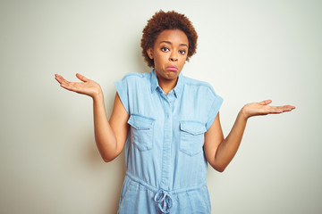 Young beautiful african american woman with afro hair over isolated background clueless and...